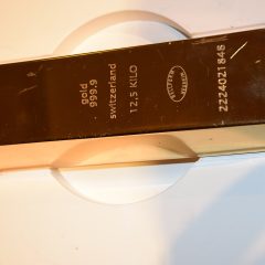 Several gold bullion bars stacked neatly on a dark surface.