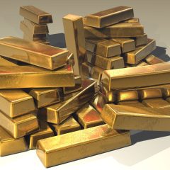 Stack of pure gold bullion bars with official purity stamps and markings.